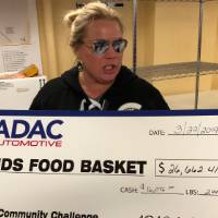 Volunteer holding a check for Kids' Food Basket